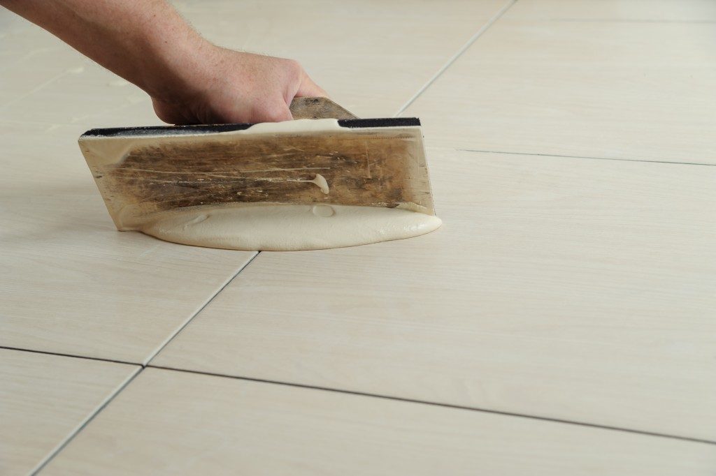 Worker filling tiles with grout