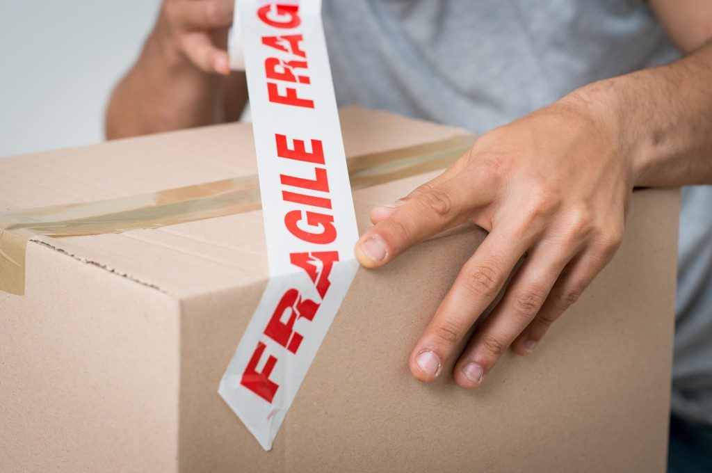 Man putting a fragile tag on the box