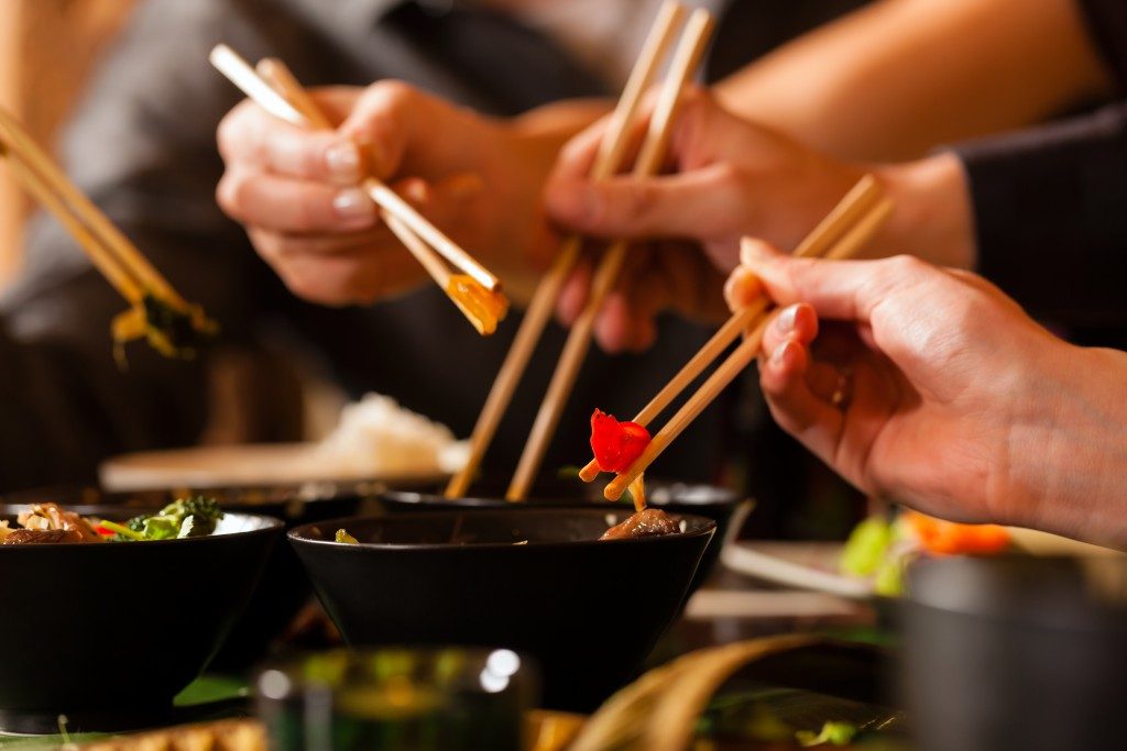 A group of people holding chopsticks