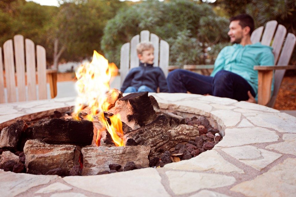 Father and son hanging out near an outdoor firepit in their yard