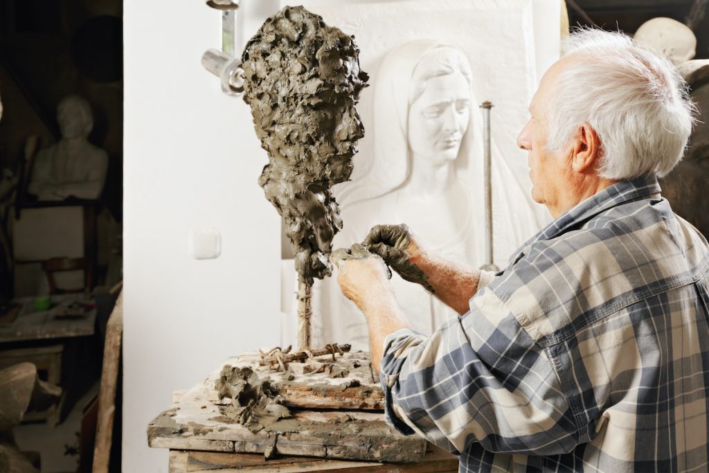 man sculpting a figure out of clay