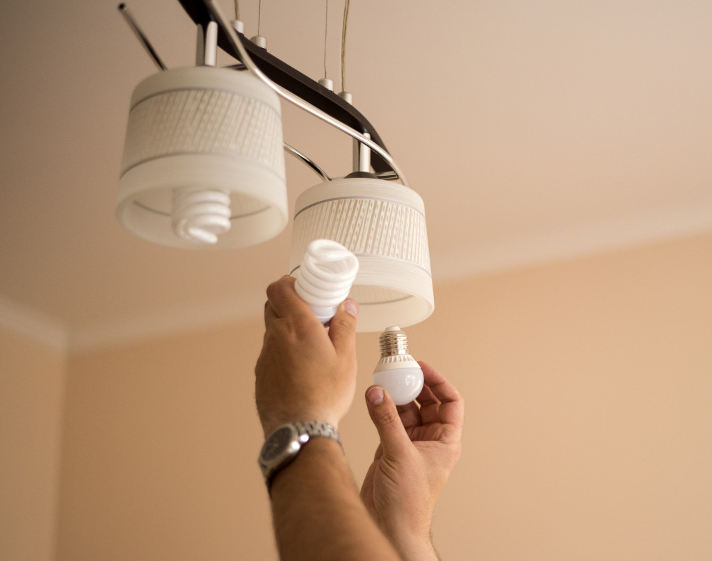A man changing the bulb of pendant lights