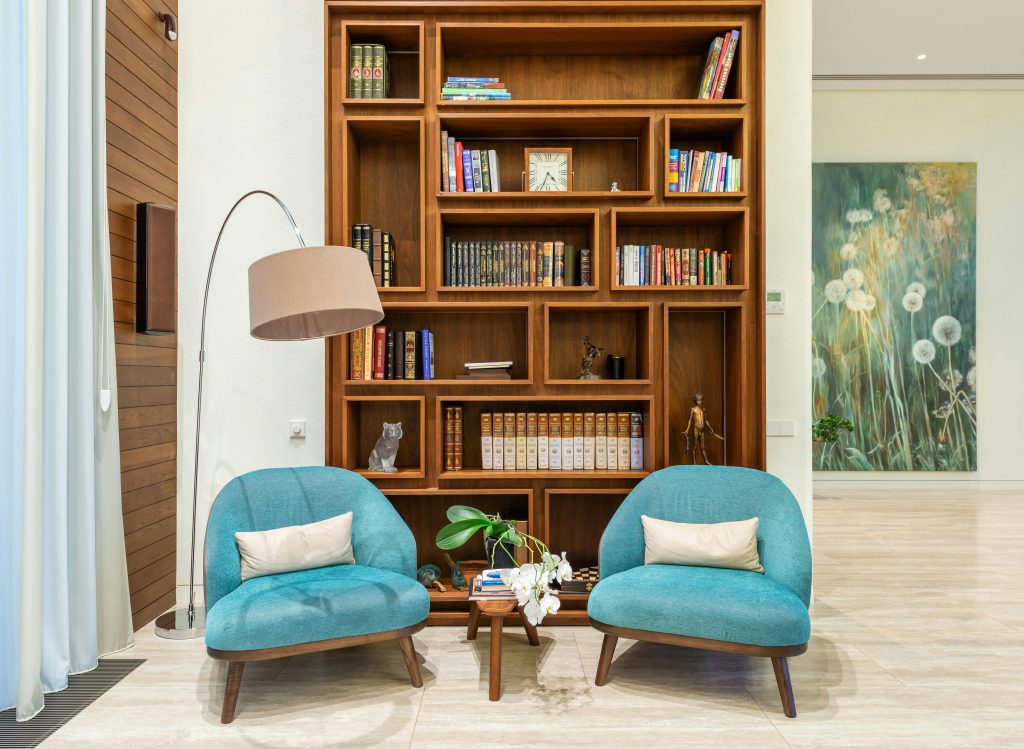 two blue seats in front of a wooden bookshelf